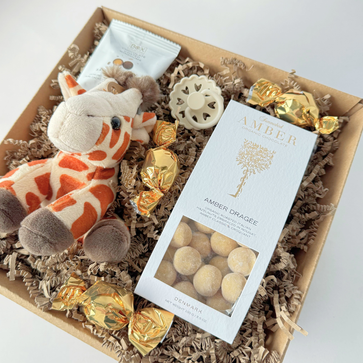 Barselsgavekurv med chokoladekugler, amber hasselnødder, sut og bamse.