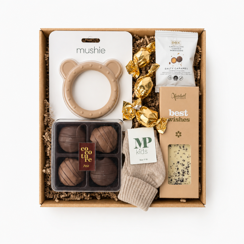Gavekurv med babyprodukter og chokolade som sød barselsgave til nybagte forældre