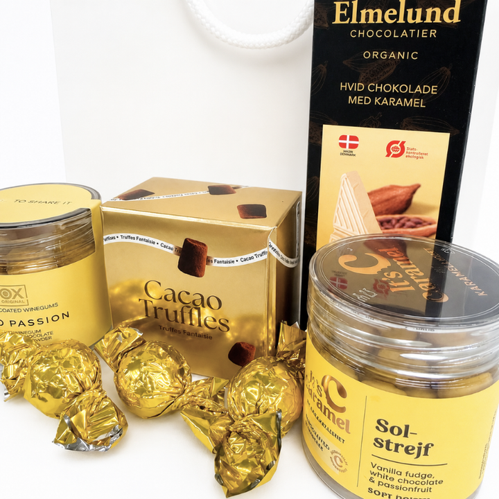 Billede af gavepose med chokolade, karamel, trøfler, mango og passionsfrugt i gule og gyldne nuancer.
