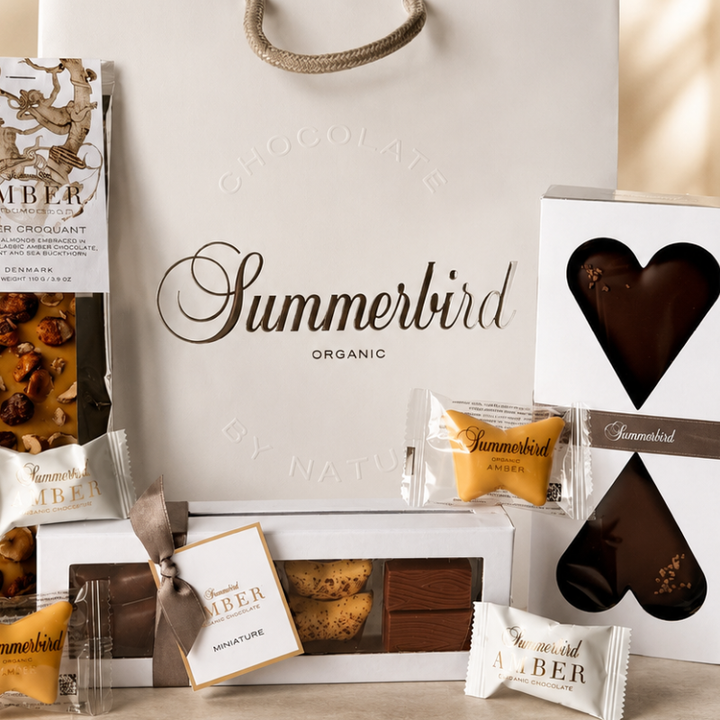 Eksklusiv chokoladegave fra Summerbird Organic med fire klassiske chokoladeprodukter og små enkeltindpakkede chokolader i hvid gavepose.